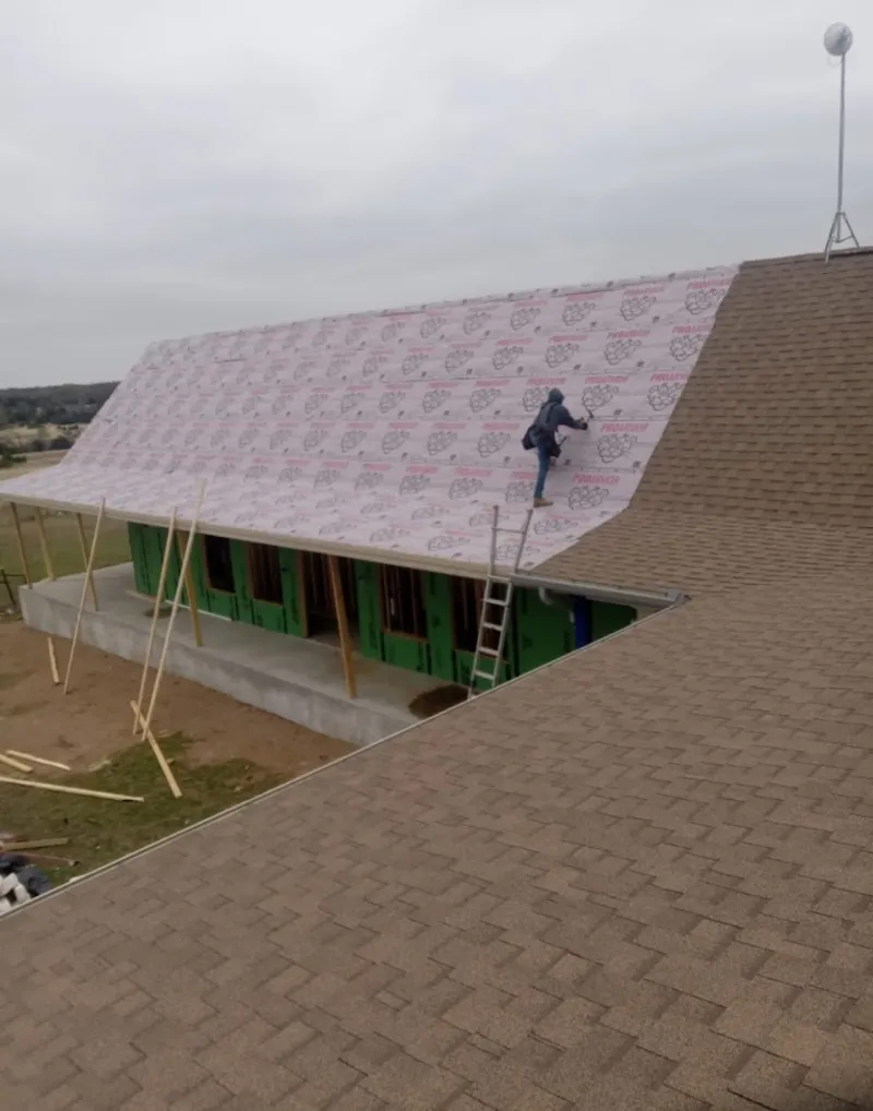 Worker preparing underlayment for a metal roof installation in Groveland